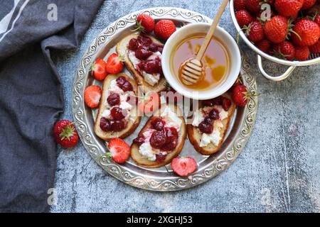 Sandwich avec fraises, fromage à pâte molle et miel sur planche de bois sur fond gris. Vue de dessus . Banque D'Images