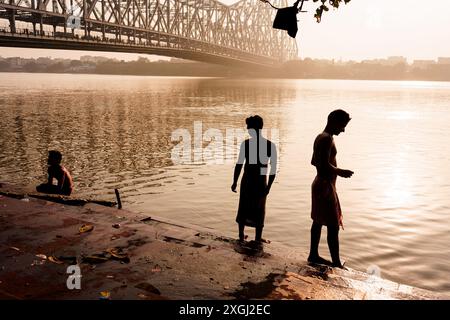 Kolkata, Inde - 3 novembre 2023 : on voit des gens jouer des pujas du matin dans la rivière Hoosely avec le pont Howrah en arrière-plan dans le Mornin Banque D'Images