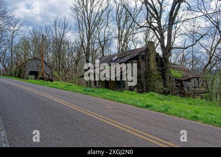 Ferme abandonnée le long de la route dans les montagnes du Tennessee avec une maison délabrée une grange intacte et un tracteur vintage en décomposition dans le grand gras Banque D'Images