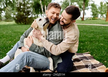 Un couple gay barbu profite d'un pique-nique dans un parc verdoyant avec leur labrador retriever. Banque D'Images