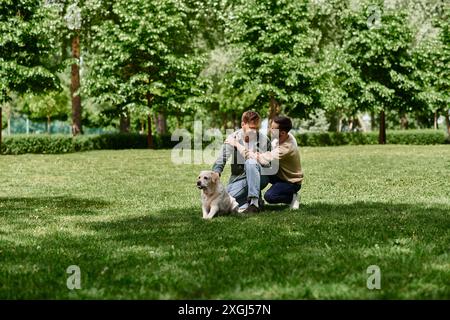 Un couple gay barbu passe du temps avec son chien labrador dans un parc verdoyant. Ils rient et apprécient les uns les autres compagnie. Banque D'Images