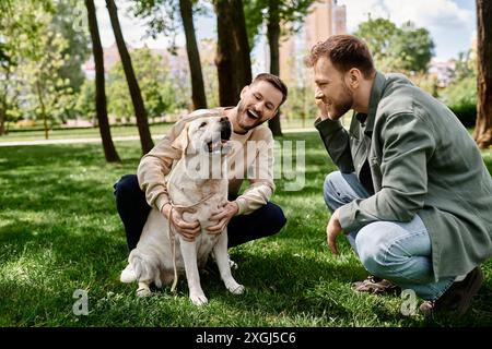 Un couple gay barbu rit ensemble dans un parc avec leur chien labrador. Banque D'Images