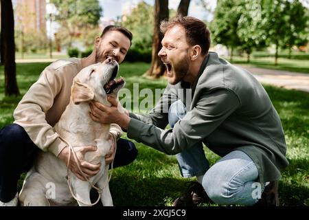 Un couple gay barbu en tenue décontractée rit avec son chien Labrador tout en passant du temps de qualité ensemble dans un parc verdoyant. Banque D'Images