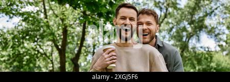 Un couple gay barbu rit ensemble tout en profitant d'une journée dans le parc. Banque D'Images