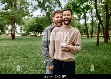 Un couple gay barbu rit ensemble dans un parc verdoyant, profitant d'une journée de détente. Banque D'Images