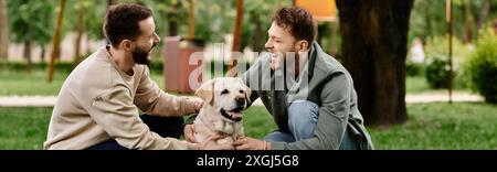 Un couple gay barbu rit ensemble dans un parc verdoyant avec leur labrador retriever. Banque D'Images