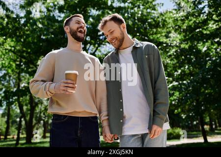 Un couple gay barbu se promène dans un parc verdoyant, riant et profitant de la compagnie des autres. Banque D'Images