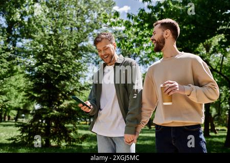 Deux hommes gays barbus marchent main dans la main à travers un parc, riant et appréciant l'un l'autre en compagnie. Banque D'Images