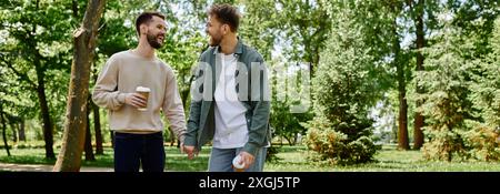 Un couple gay barbu marche main dans la main dans un parc par une journée ensoleillée, profitant de la compagnie de l'autre. Banque D'Images