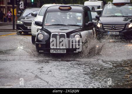 Londres, Royaume-Uni. 9 juillet 2024. Un taxi jaillit dans une grande flaque d'eau sur Euston Road alors que de fortes pluies inondent la capitale. Crédit : Vuk Valcic/Alamy Live News Banque D'Images