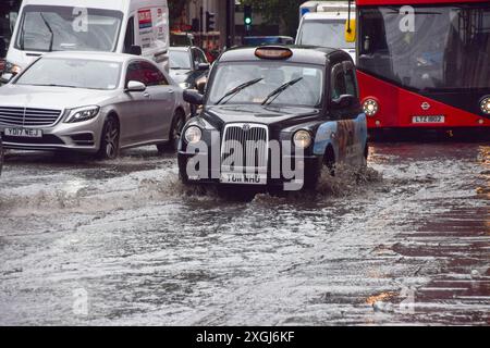 Londres, Royaume-Uni. 9 juillet 2024. Un taxi jaillit dans une grande flaque d'eau sur Euston Road alors que de fortes pluies inondent la capitale. Crédit : Vuk Valcic/Alamy Live News Banque D'Images