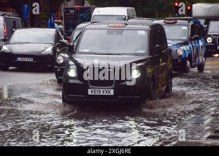 Londres, Royaume-Uni. 9 juillet 2024. Un taxi jaillit dans une grande flaque d'eau sur Euston Road alors que de fortes pluies inondent la capitale. Crédit : Vuk Valcic/Alamy Live News Banque D'Images