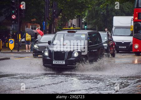 Londres, Royaume-Uni. 9 juillet 2024. Un taxi jaillit dans une grande flaque d'eau sur Euston Road alors que de fortes pluies inondent la capitale. Crédit : Vuk Valcic/Alamy Live News Banque D'Images