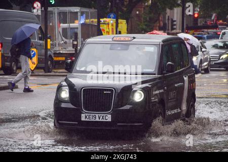 Londres, Royaume-Uni. 9 juillet 2024. Un taxi jaillit dans une grande flaque d'eau sur Euston Road alors que de fortes pluies inondent la capitale. Crédit : Vuk Valcic/Alamy Live News Banque D'Images