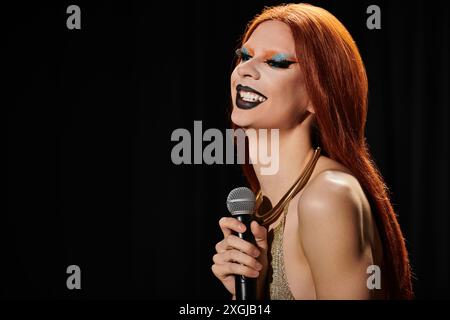 Une drag queen dans une robe dorée à sequins tient un micro et rit. Banque D'Images