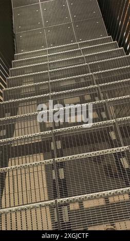 Une vue rapprochée d'un escalier métallique avec un motif de grille, montrant les détails complexes de la construction. Photo mobile verticale. sstkvertical Banque D'Images