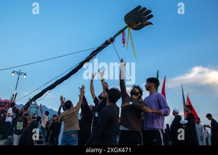 Srinagar, Inde. 09 juillet 2024. Les musulmans chiites du Cachemire tiennent un drapeau islamique installé sur la route de l'estran à Srinagar. Mouharram est le premier mois du calendrier islamique. C'est l'un des mois les plus saints du calendrier islamique. Les musulmans chiites commémorent Mouharram comme un mois de deuil en souvenir du martyre du petit-fils du prophète islamique Mahomet, Imam Hussain, qui a été tué à Ashura (10e jour de Muharram) dans la bataille de Karbala en 680 après J.-C. crédit : SOPA images Limited/Alamy Live News Banque D'Images