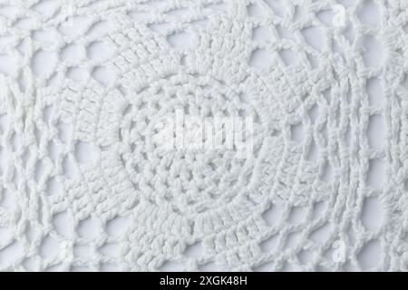 Un morceau de tissu crocheté blanc avec un motif d'une fleur. La fleur est composée de nombreux petits cercles Banque D'Images