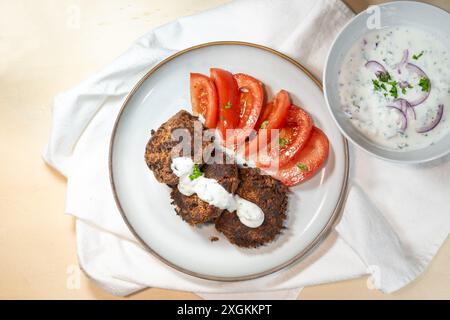 Galettes végétariennes à base de haricots rouges avec des tomates et une trempette de yaourt sur une assiette, repas sain avec beaucoup de protéines et de fibres alimentaires, haute ang Banque D'Images