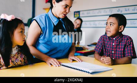 Enseignant aidant les enfants élèves à apprendre à lire en classe à la salle d'école maternelle. Concept multiracial et éducatif. Focus sur le visage de l'enfant africain Banque D'Images