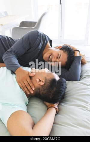 Couple gay biracial et moyen-oriental relaxant à la maison, avec espace de copie. Ils partagent un moment joyeux, exsudant chaleur et compagnie. Banque D'Images