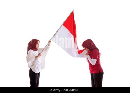 Portrait d'une femme tenant le drapeau indonésien et l'embrassant comme un symbole de fierté du jour de l'indépendance de l'Indonésie isolé sur fond blanc Banque D'Images