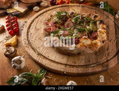 Pizza Mortadella avec tomates séchées au soleil et pesto décorée avec aragula sur planche de bois Banque D'Images