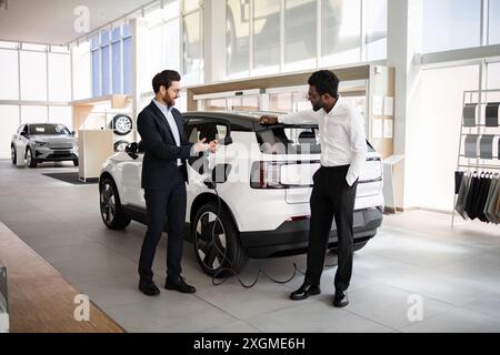 Concessionnaire vend SUV électrique à l'homme d'affaires dans la concession automobile moderne Banque D'Images