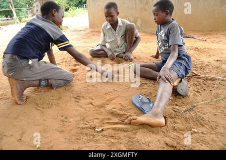 Enfants jouant à Nxtuva, Licaca, Inhambane, Mozambique. Nxtuva est membre de Mancala, une famille de jeux de stratégie à deux joueurs au tour par tour. Banque D'Images