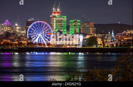 Vieux-Port de Montréal et horizon du centre-ville la nuit. Les lumières colorées des bâtiments se reflètent dans l'eau. Montréal, Québec, Canada. Banque D'Images