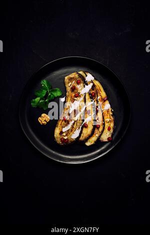 Tranches d'aubergines frites, avec sauce blanche, sur fond noir, vue de dessus, verticalement, sans personne Banque D'Images