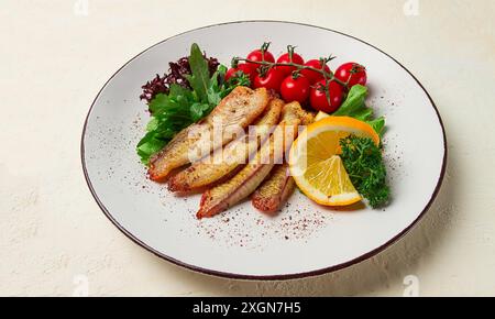 Filet de poisson frit de Tilapia, aux épices, avec cerise et salade, sur une assiette blanche, fait maison, pas de gens Banque D'Images