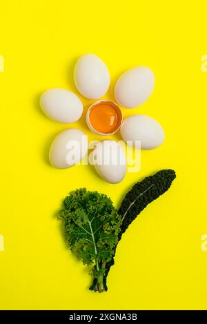 Oeufs frais, sur fond jaune, en forme de camomille avec des feuilles de chou, vue de dessus, verticalement, sans personnes, fond alimentaire Banque D'Images