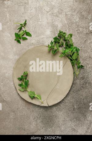 Plaque d'argile grise, fait à la main, avec des branches de basilic, vue de dessus, fond de nourriture, papier peint alimentaire pour le menu Banque D'Images