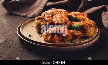 Cuisses de poulet frites, panées, avec des épices et des herbes, sur un fond sombre, horizontal, sans personne, mise au point sélective, tonifiée Banque D'Images