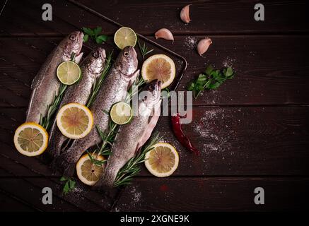 Truite arc-en-ciel crue, avec du citron et des herbes, sur une table en bois, pas de gens Banque D'Images