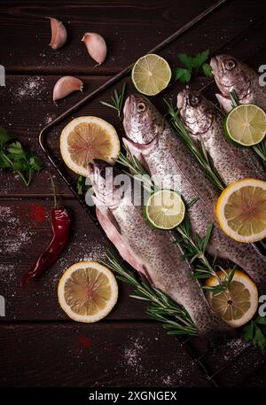 Truite arc-en-ciel crue, avec du citron et des herbes, sur une table en bois, pas de gens Banque D'Images