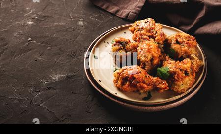 Cuisses de poulet frites, panées, avec des épices et des herbes, sur un fond sombre, horizontal, sans personne, mise au point sélective, tonifiée Banque D'Images