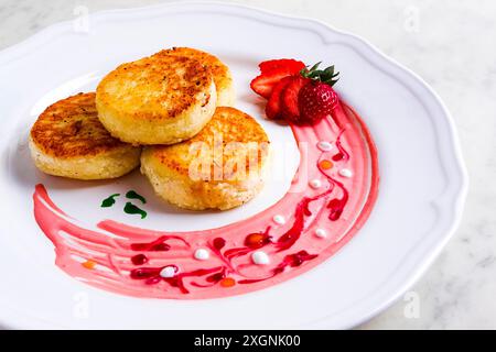 Crêpes au fromage cottage, sur une assiette blanche décorée de sauce, fraise fraîche, gros plan, pas de gens Banque D'Images