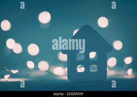 Hiver, minuscule maison de jouet sur fond de lumières de Noël la nuit Banque D'Images