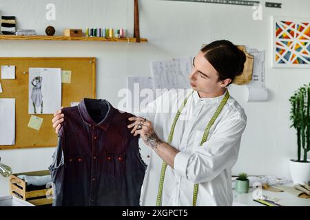 Un jeune homme examine un vêtement jeté, prêt à lui donner une nouvelle vie dans son atelier de mode durable. Banque D'Images