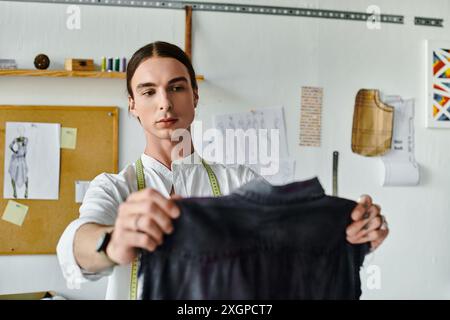Un jeune homme examine méticuleusement un morceau de tissu dans son atelier de restauration de vêtements DIY, engagé à donner une nouvelle vie aux vêtements jetés. Banque D'Images