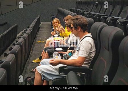 Les enfants s'assoient dans la salle de cinéma portant des lunettes 3D avec du pop-corn et un verre avant de regarder. week-end en famille Banque D'Images