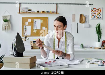 Un jeune homme examine méticuleusement un morceau de tissu, prêt à le transformer en quelque chose de nouveau dans son atelier de restauration de vêtements durables. Banque D'Images