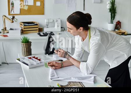 Un jeune homme examine méticuleusement un morceau de tissu dans son atelier de restauration de vêtements. Banque D'Images