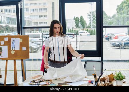 Un jeune homme examine méticuleusement un morceau de tissu dans son atelier de restauration de vêtements, montrant son dévouement à la durabilité et donnant de nouveaux Li Banque D'Images