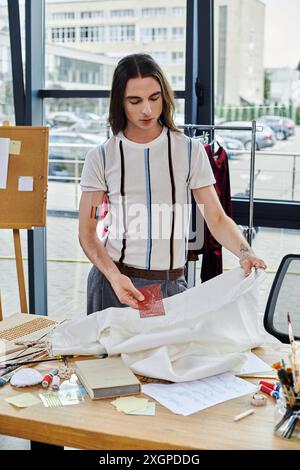 Un jeune homme examine méticuleusement un morceau de tissu dans son atelier de restauration de vêtements. Axé sur la durabilité, il insuffle une nouvelle vie à jeter Banque D'Images