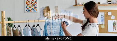 Un jeune homme gay examine méticuleusement un vêtement dans son atelier de restauration de vêtements DIY, mettant en valeur sa passion pour la durabilité et le givin Banque D'Images