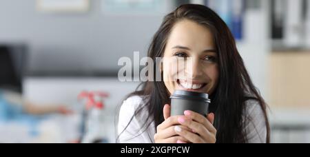 Femme souriante tenir le papier noir moog avec le portriat de boisson de café. Concept d'énergie matinale Banque D'Images