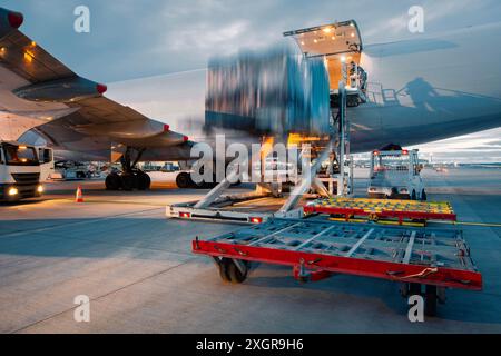 Préparation gros avion cargo avant le vol. Déchargement et chargement de conteneurs de fret à l'aéroport. Banque D'Images